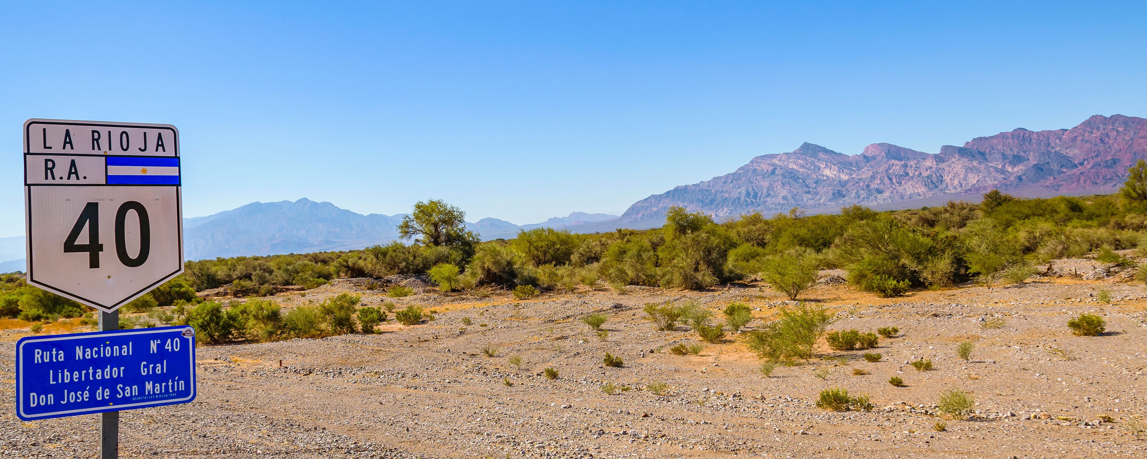 A road sign for Ruta Nacional N°40 in La Rioja, R.A., with a mountainous landscape in the background.
