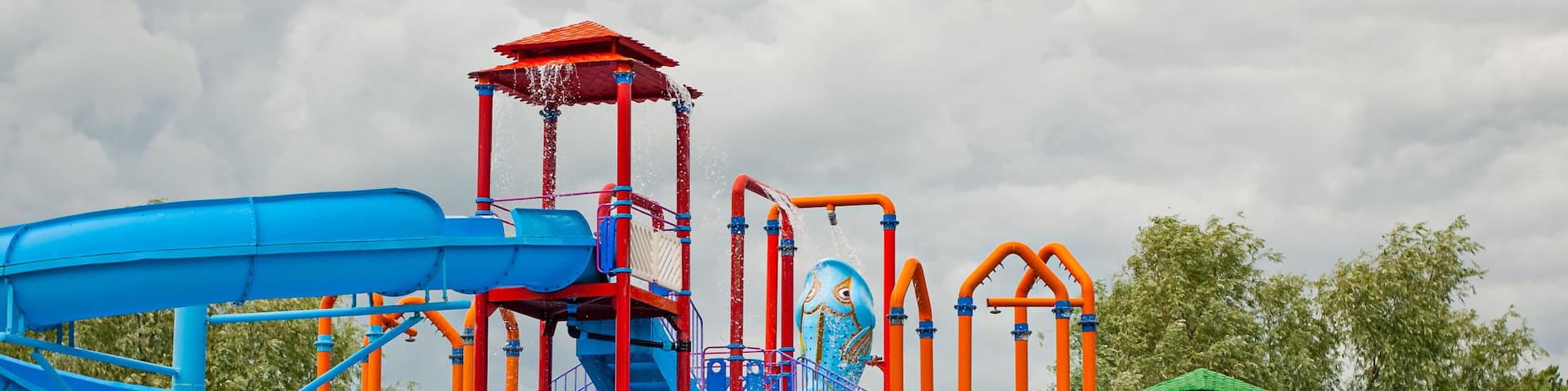 Un parque acuático colorido con toboganes azules y naranjas y una estructura de juego verde.