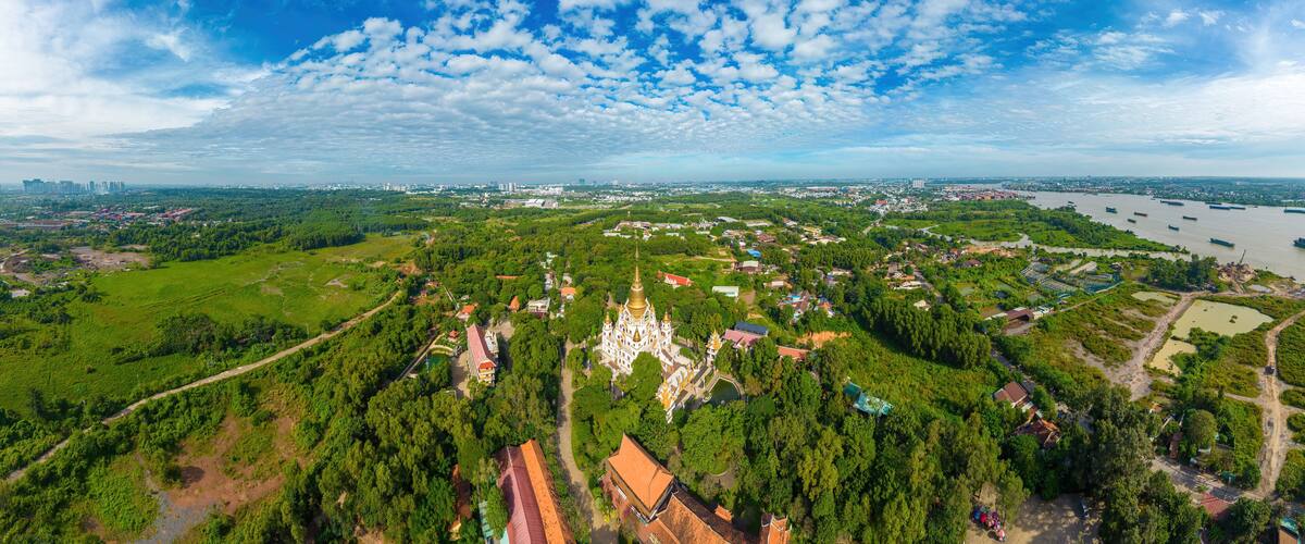 An aerial view of a city with a river, green areas, and a prominent white church with a golden dome.