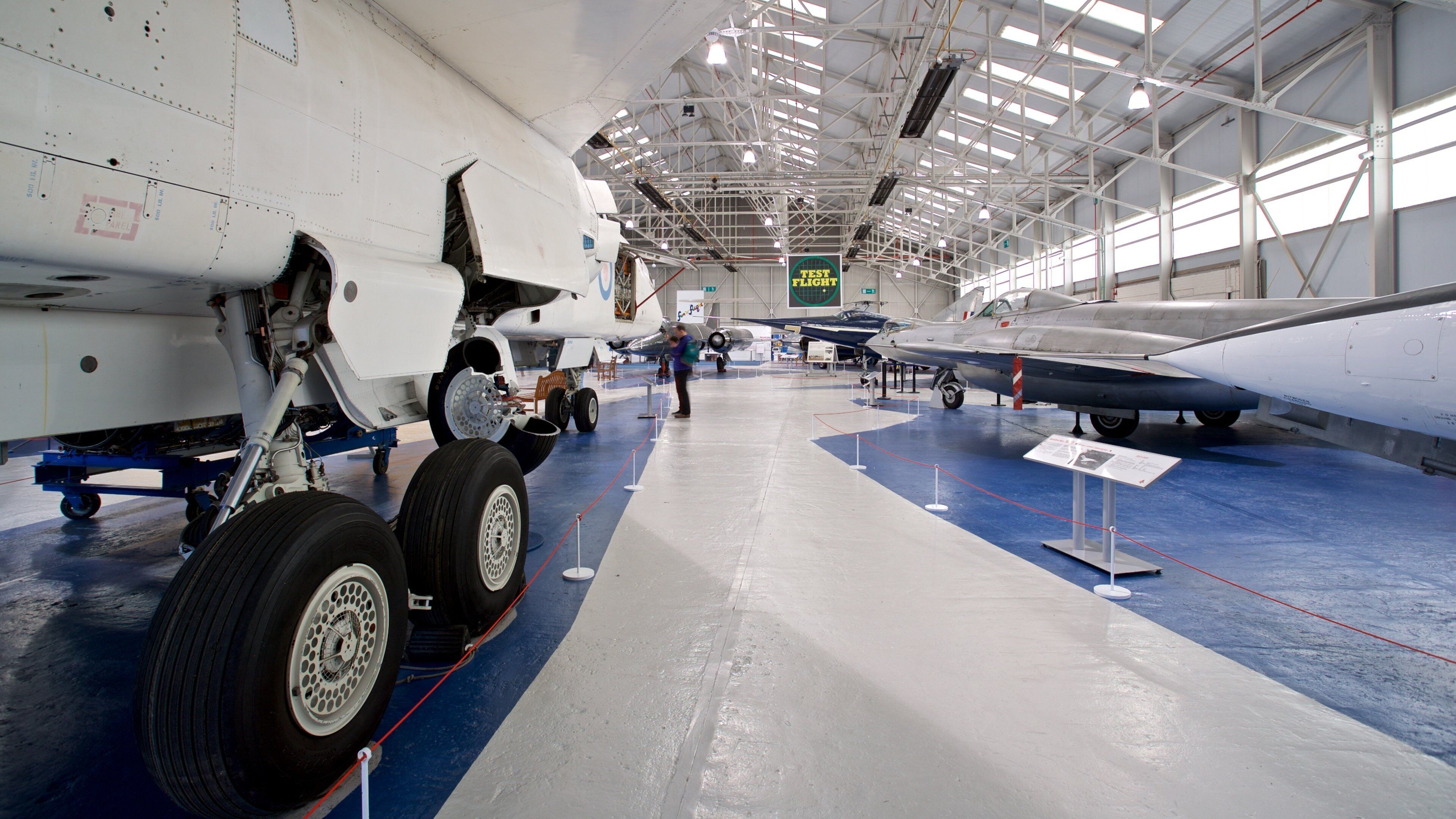 Een vliegtuig hangar met diverse vliegtuigen tentoongesteld, waaronder een groot transportvliegtuig en een jachtvliegtuig.