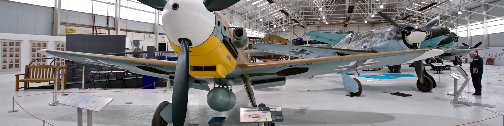 A vintage aircraft on display in a museum with other planes in the background.