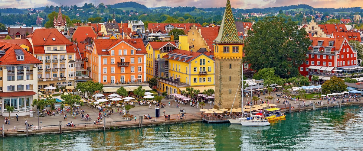 Lindau, Germany. Antique Bavarian town in Bavaria at coastline of Lake Constance (Bodensee). Habour along embankment with traditional houses and tower. Sunset evening landscape.
