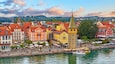 Lindau, Germany. Antique Bavarian town in Bavaria at coastline of Lake Constance (Bodensee). Habour along embankment with traditional houses and tower. Sunset evening landscape.