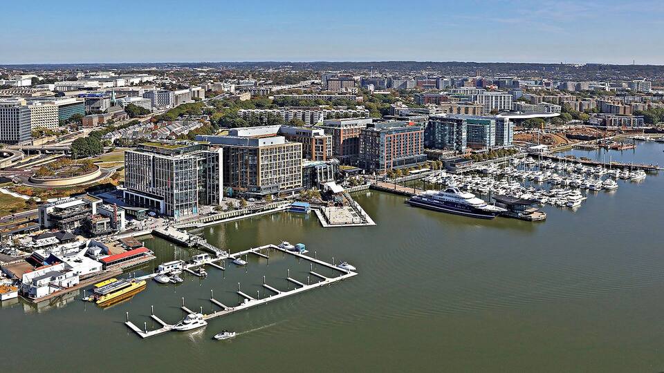 A marina with boats, a large cruise ship, and surrounding urban buildings.