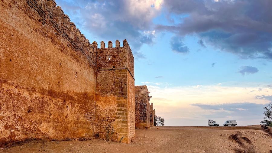 A view of the walls and towers of the Boulaouane Kasbah in the evening light. 2 expedition 4x4s have set up camp at the foot of the fortress