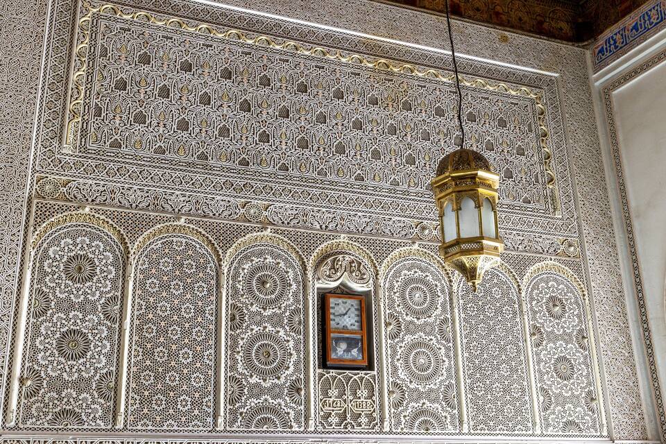 An intricately designed wall with geometric patterns and a hanging lantern.