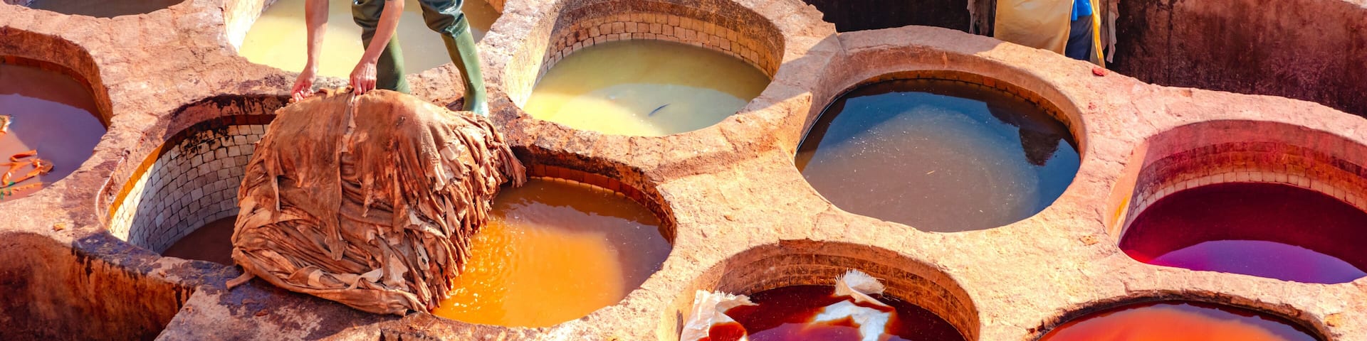 Un área tradicional para teñir con varias tinas circulares y trabajadores procesando textiles.
