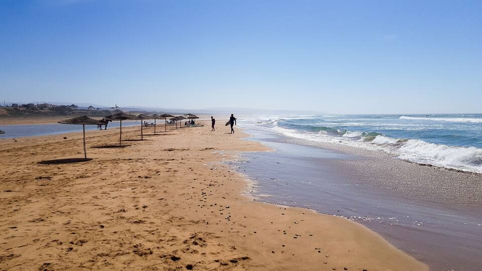 A sandy beach with umbrellas and footprints.
