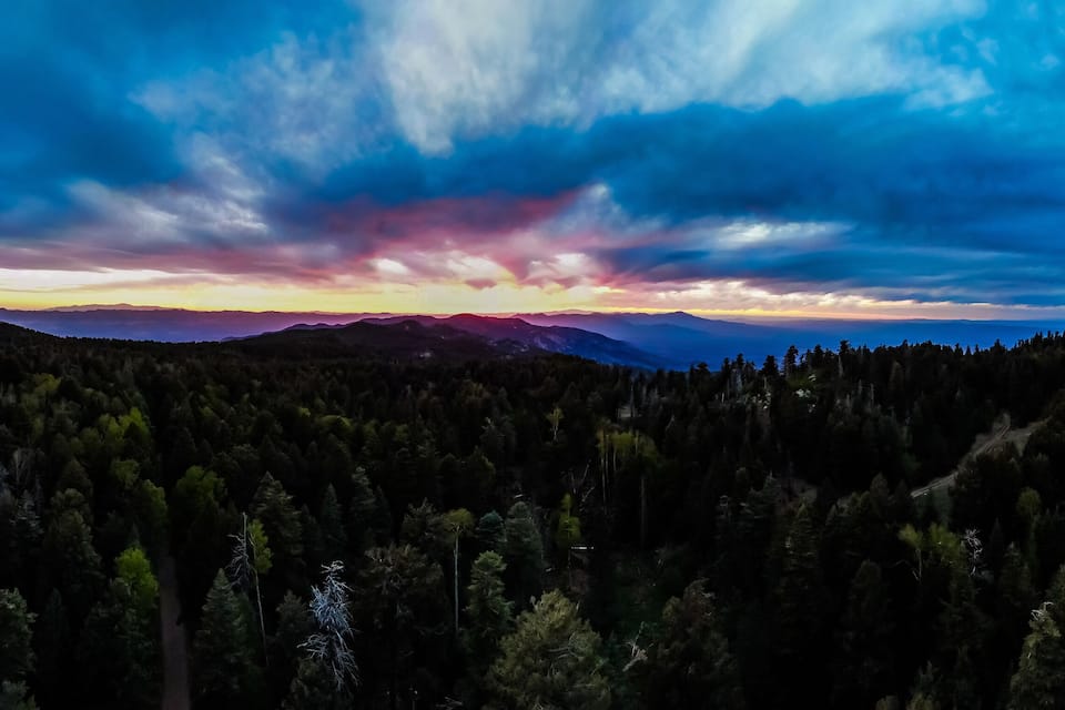 A forested mountain range with a sunset sky.