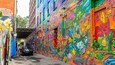 A narrow alley with colorful graffiti on the walls.