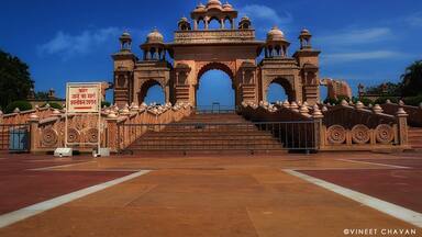 A grand entrance with intricate arches and domes, a flag on top, and a sign in a foreign language.