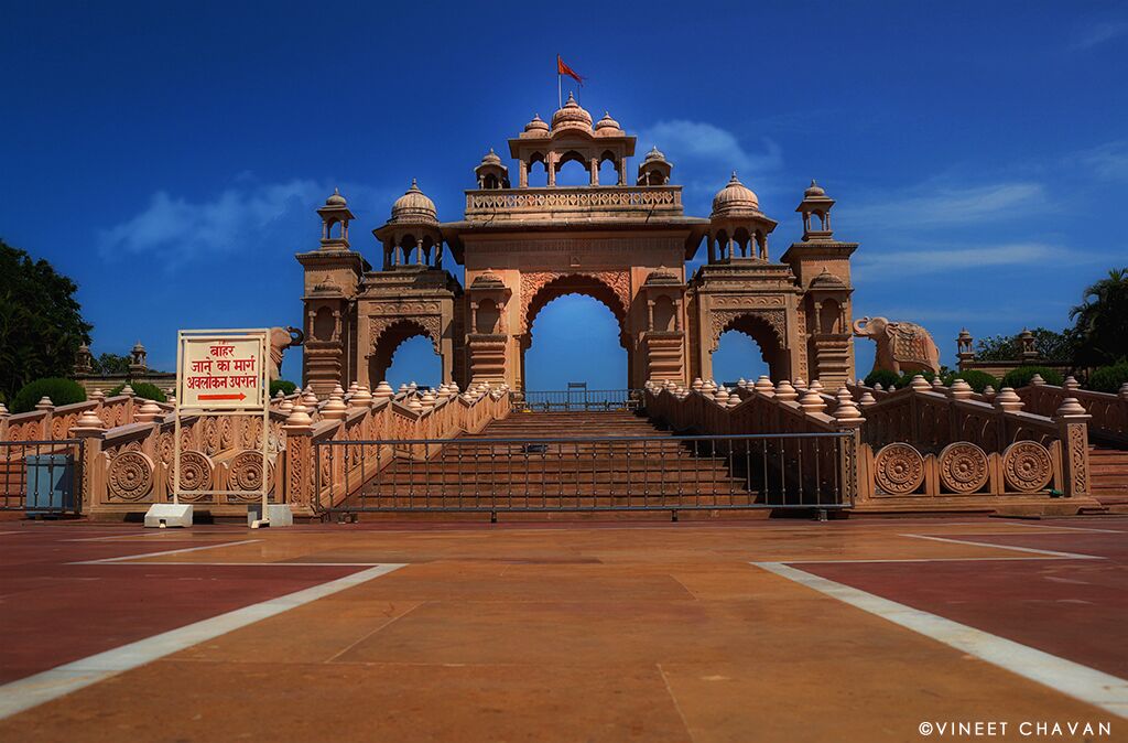 A grand entrance with intricate arches and domes, a flag on top, and a sign in a foreign language.
