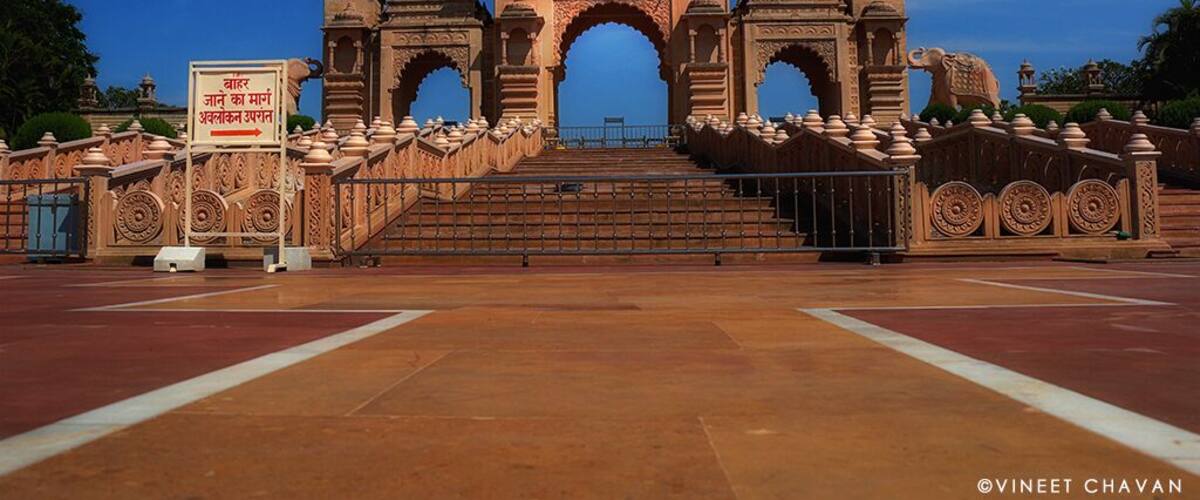 A grand entrance with intricate arches and domes, a flag on top, and a sign in a foreign language.