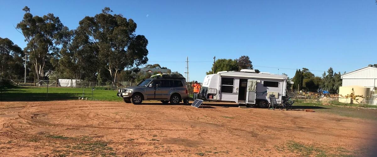 A dirt field with a parked SUV and a white RV.