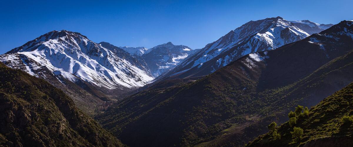 A mountainous landscape with snow-capped peaks and lush green valleys.