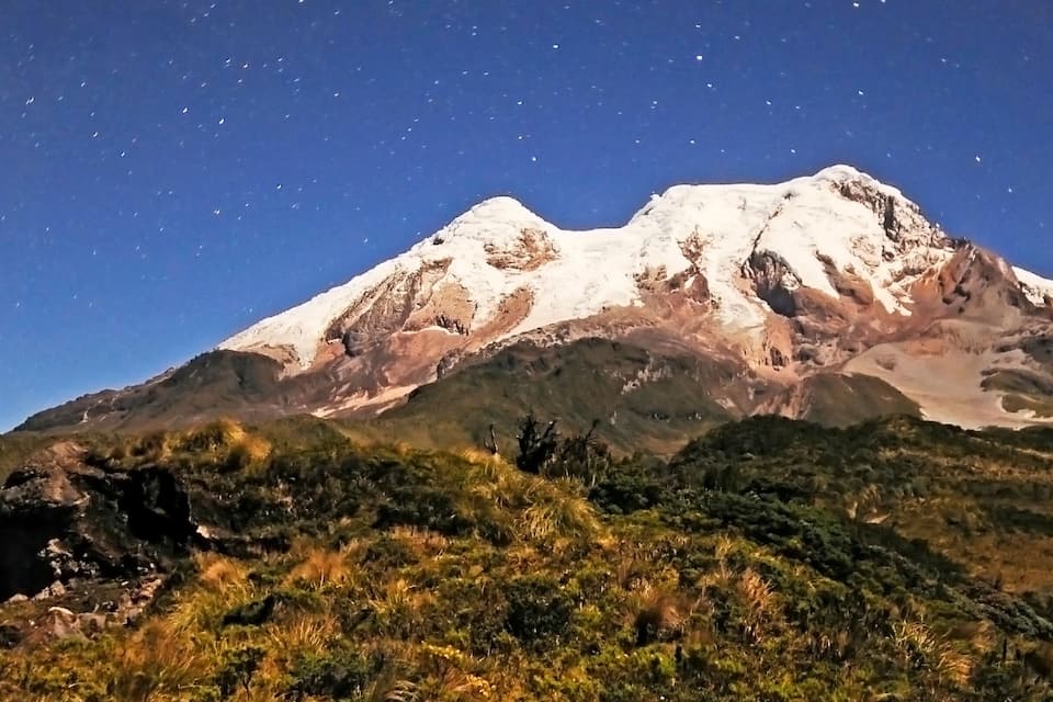 A snow-capped mountain with a clear night sky.
