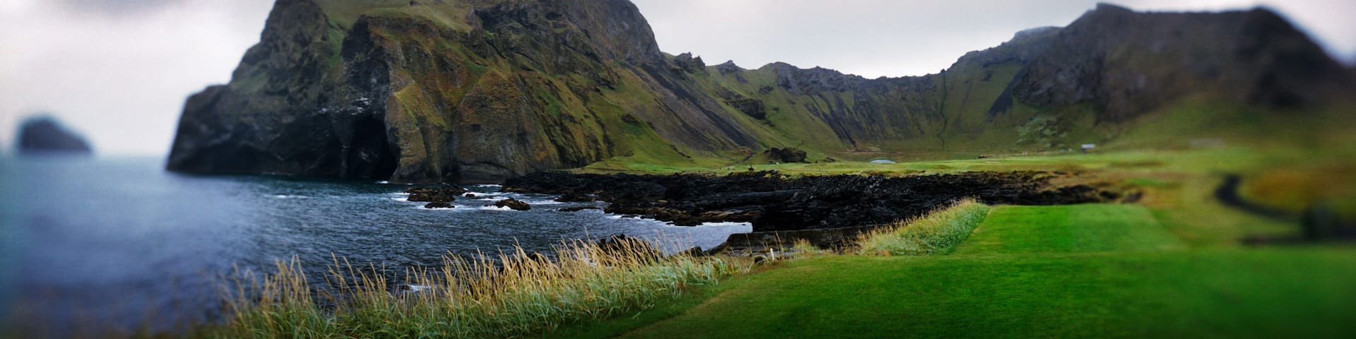 Panoramic green landscape along the coastline, Heimaey island, Westman Islands, Iceland.