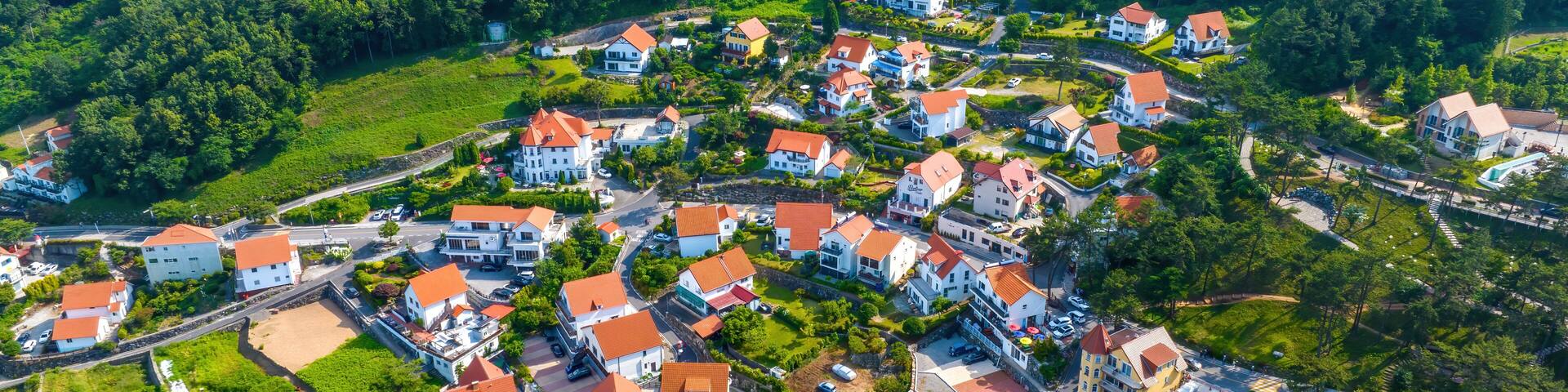 Mulgeon-ri, Namhae-gun, Gyeongsangnam-do, South Korea - June 18, 2023: Aerial and summer view road and of houses with orange roof at German Village on the hill and mountain