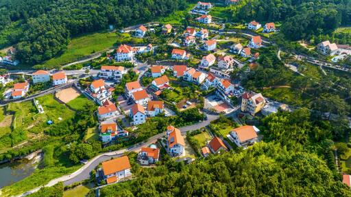 Mulgeon-ri, Namhae-gun, Gyeongsangnam-do, South Korea - June 18, 2023: Aerial and summer view road and of houses with orange roof at German Village on the hill and mountain