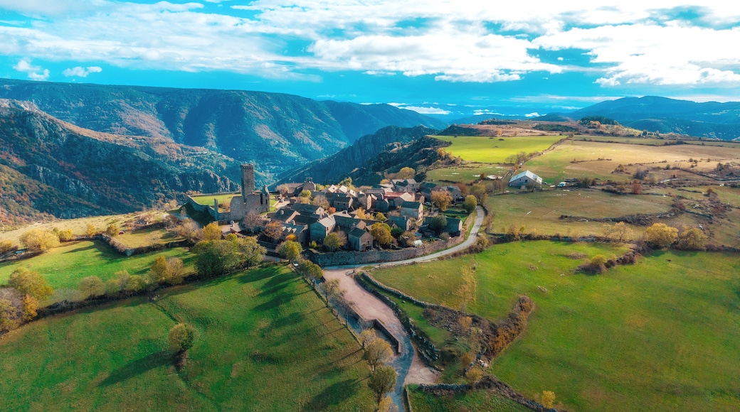 Un pueblo con una iglesia destacada, rodeado de campos verdes y montañas al fondo.