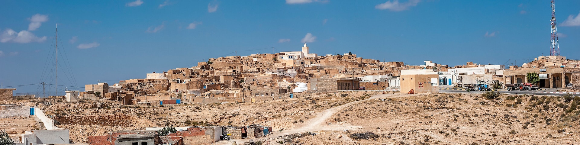 Un pueblo ondulante con edificios, una mezquita y una torre de comunicaciones.