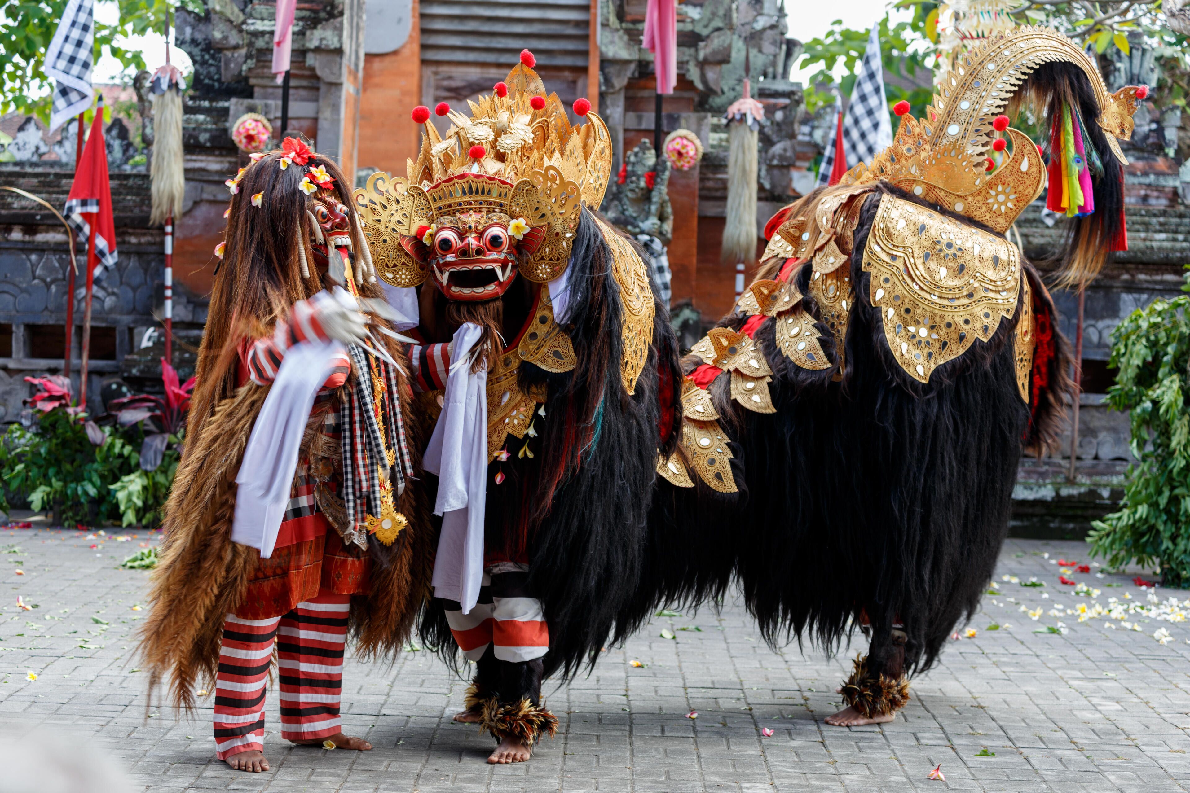 A person in a traditional costume with a large, ornate headdress and a black, furry costume.