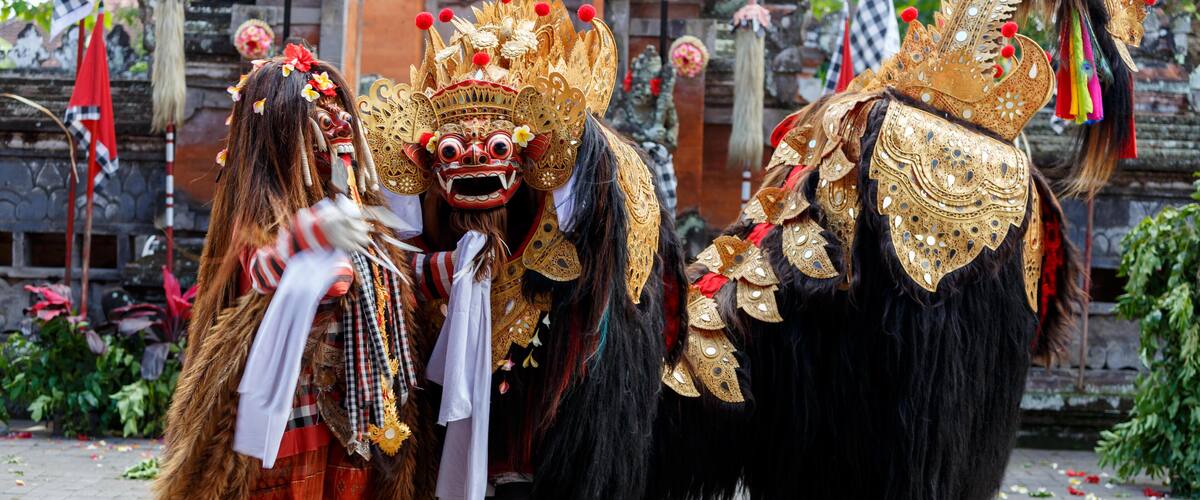A person in a traditional costume with a large, ornate headdress and a black, furry costume.