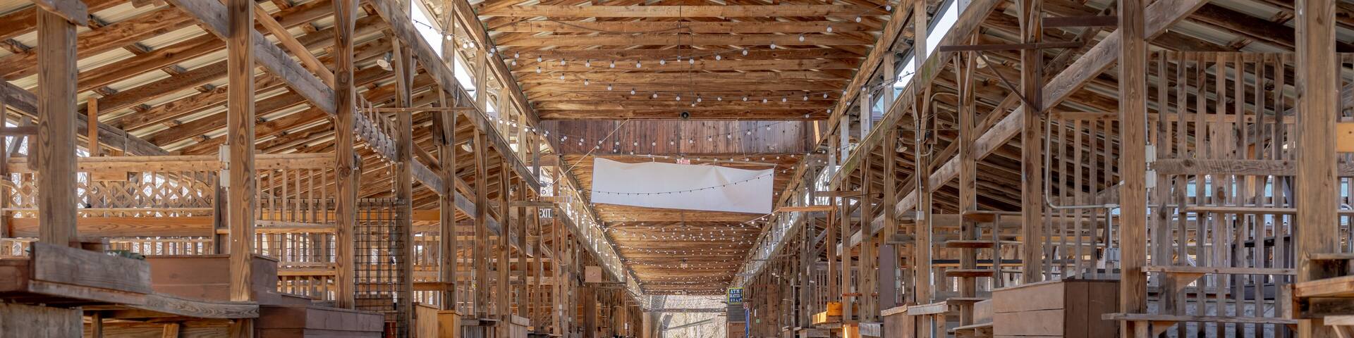 Empty open air farmers market wooden stalls within a pavilion on a bright sunny day.
