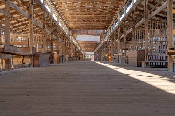 Empty open air farmers market wooden stalls within a pavilion on a bright sunny day.