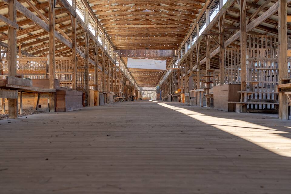 An interior view of a wooden structure with a high ceiling and a long, open space.