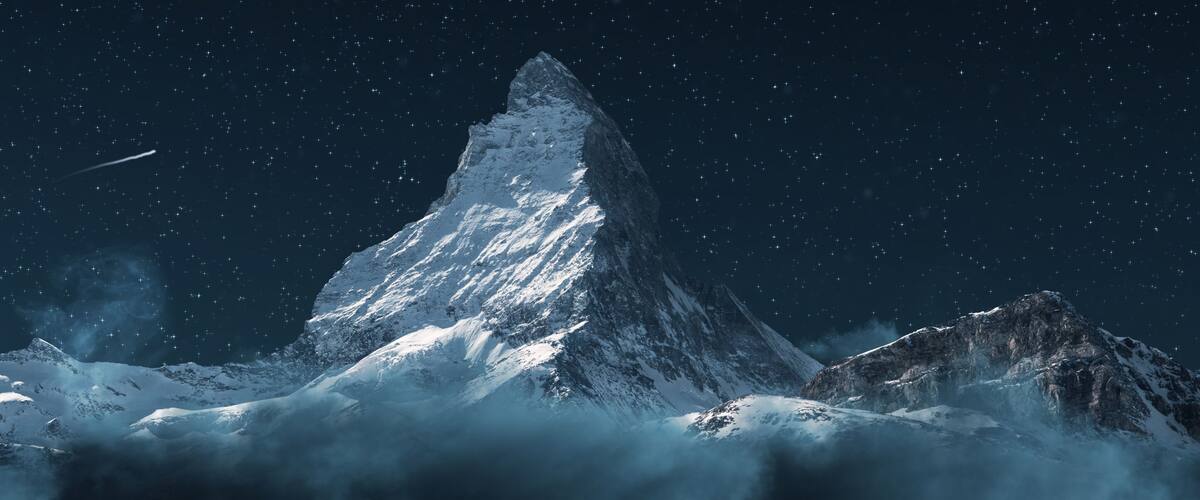A snow-covered mountain peak under a starry night sky.