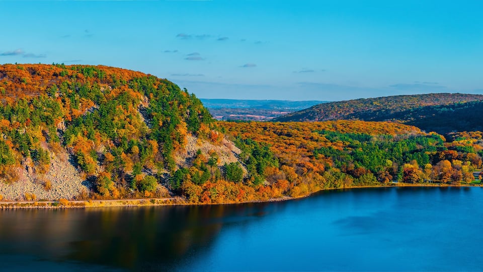A lake surrounded by hills with autumn foliage.