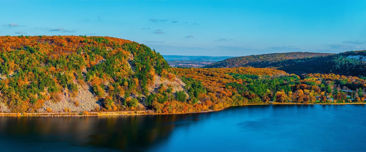 A lake surrounded by hills with autumn foliage.