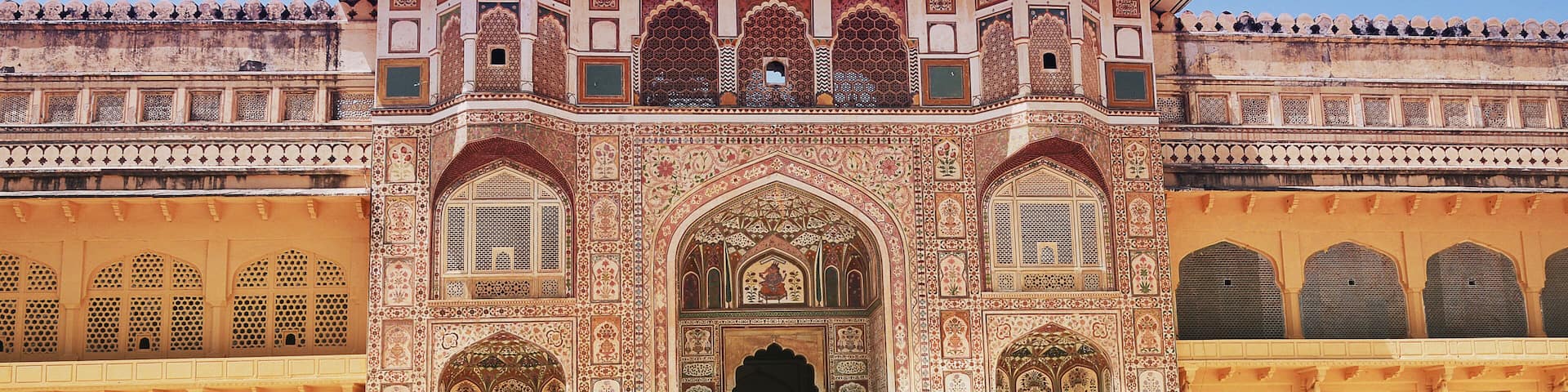 A historic building with intricate architecture, a central archway, and a person in traditional attire.