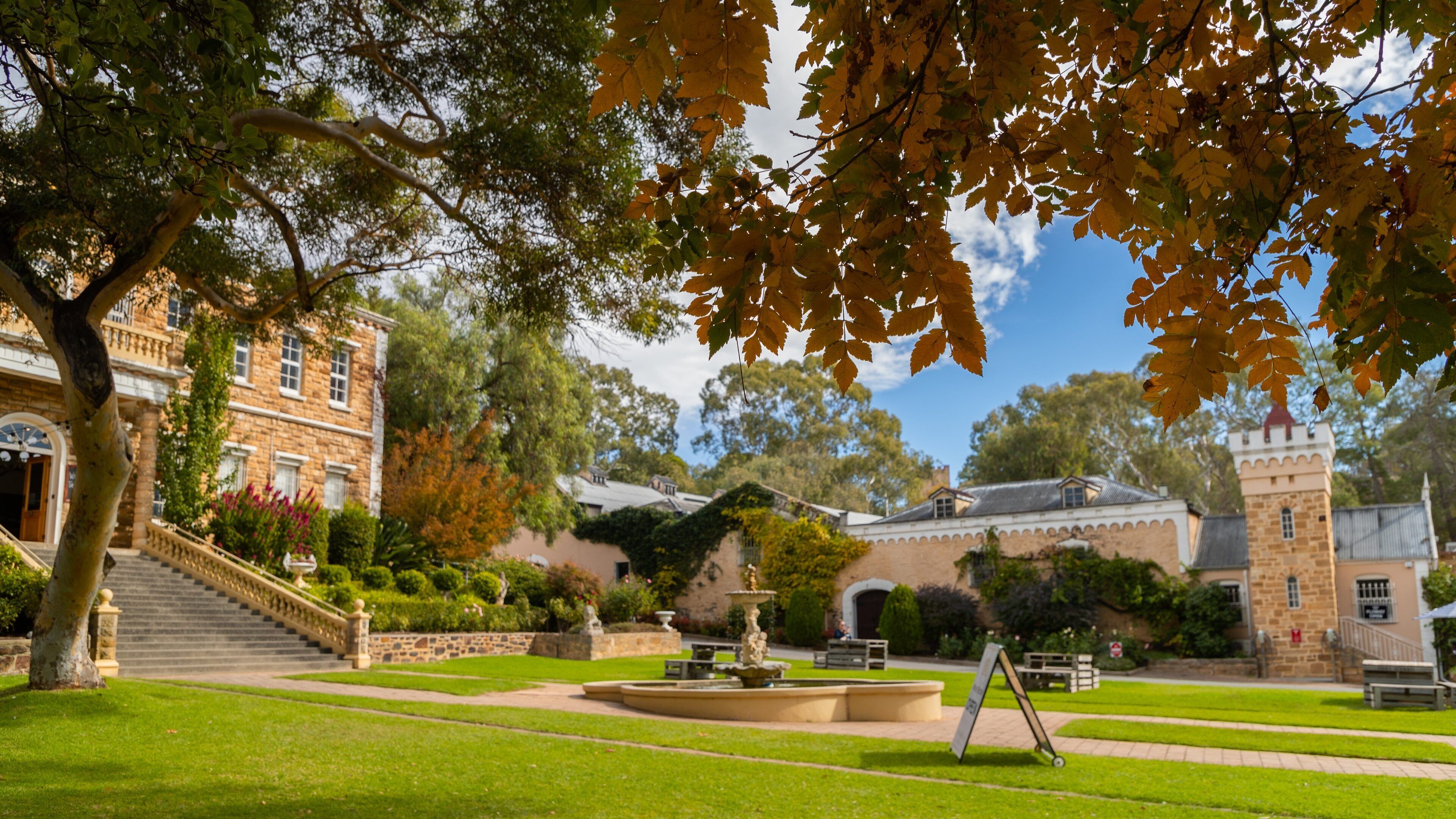 A historic building with a tower, surrounded by well-maintained gardens and a fountain.