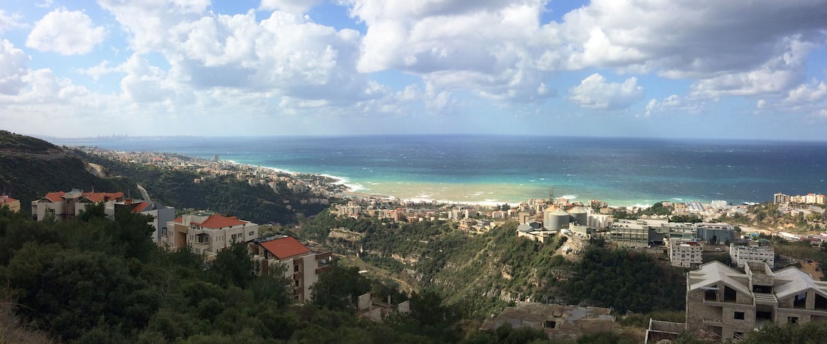 A coastal city with a beach, buildings, and hills.