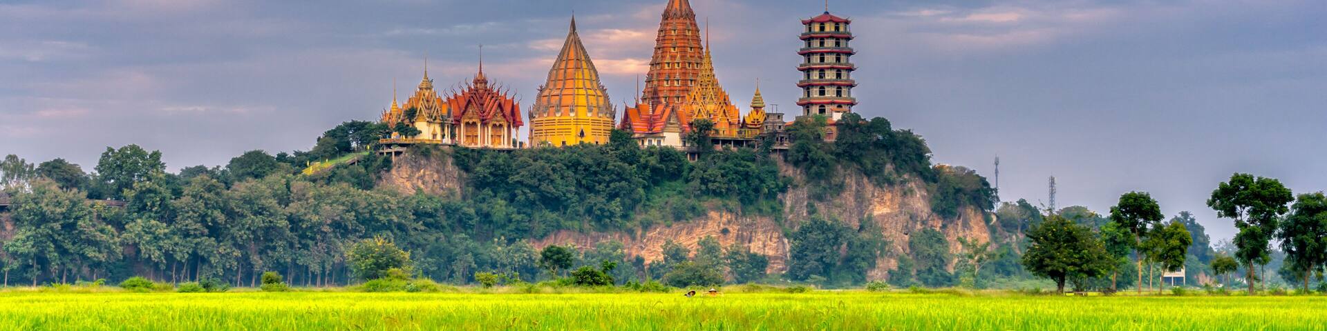 Sunset scence of Wat Tham Sua Temple with rice fields in Kanchanaburi Province, Thailand.