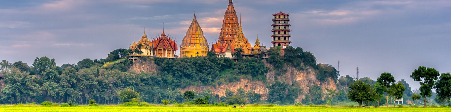 Sunset scence of Wat Tham Sua Temple with rice fields in Kanchanaburi Province, Thailand.