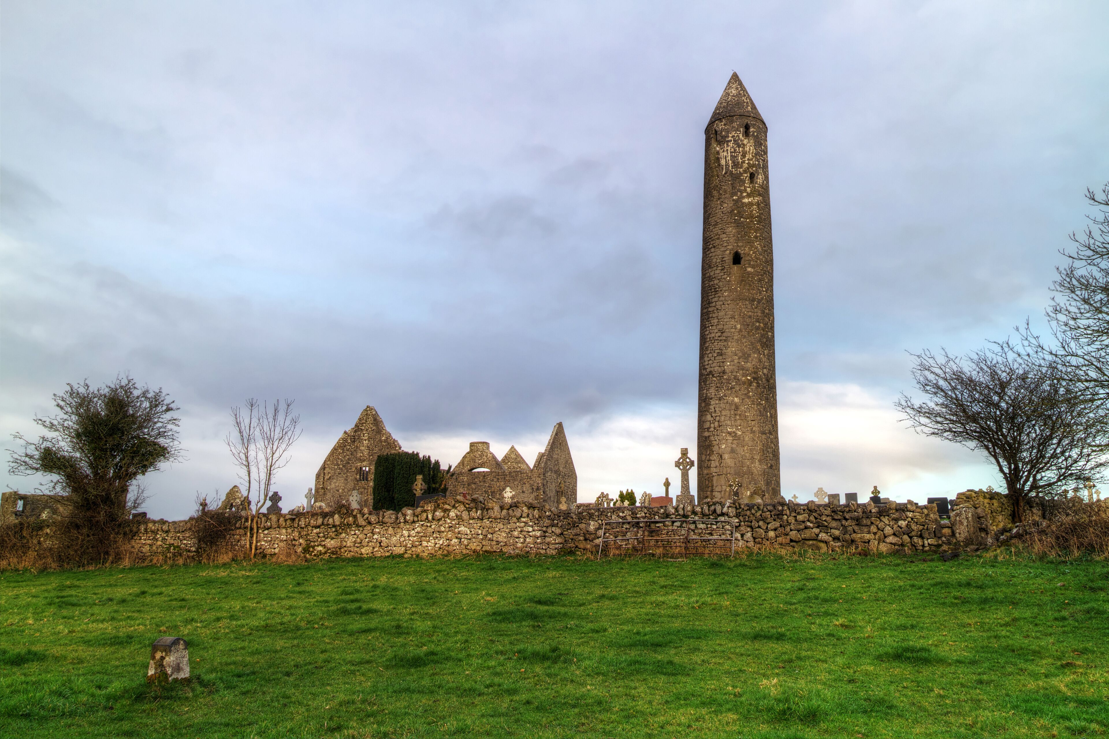 A historic stone tower and ruins in a grassy field.