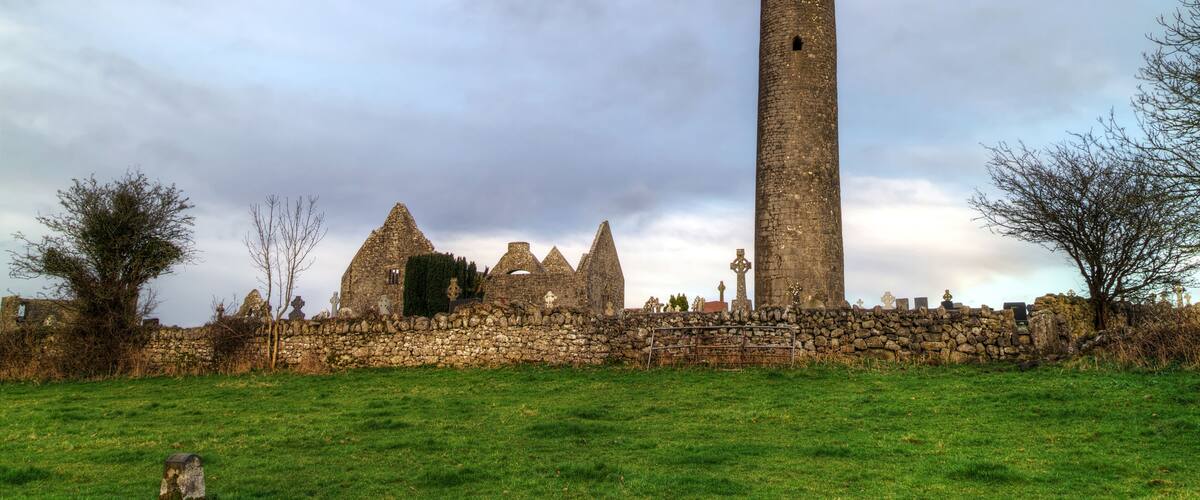 A historic stone tower and ruins in a grassy field.