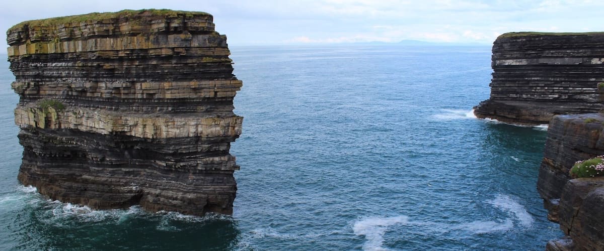 A coastal cliff formation with layered rock strata.