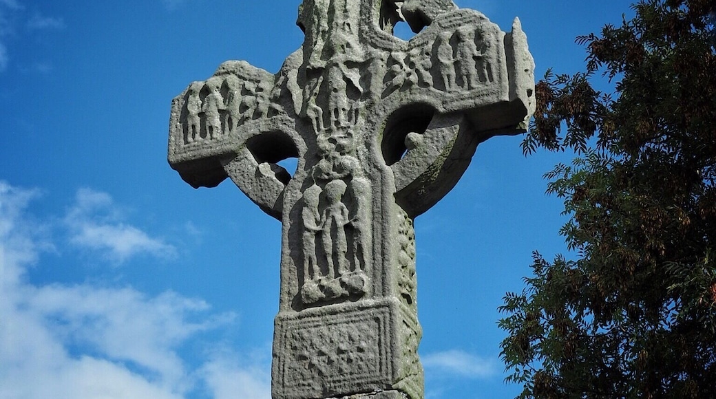 Ardboe High Cross (Irish: Seanchrois Ard Bó) is a high cross and national monument dating from the tenth century located in Ardboe, County Tyrone, Northern Ireland. The cross stands at the entrance to a cemetery and a monastery and a church from the seventeenth century which was founded in 590 by Saint Colman. The monastery was destroyed by fire in the twelfth century. It is believed to have been erected in either the ninth or the tenth century. The name "Ard Boe" means "hill of the cow" it comes from a legend that the monastery of Ardboe was built from the milk of a magic cow out of Lough Neagh and forms the only remaining part of an early monastery on the site. At around 18.5 feet (5.6 m), Ardboe High Cross is Northern Ireland's tallest cross. Although the head of the cross is damaged, it seems to be the only such cross in Northern Ireland to remain largely complete and original.
