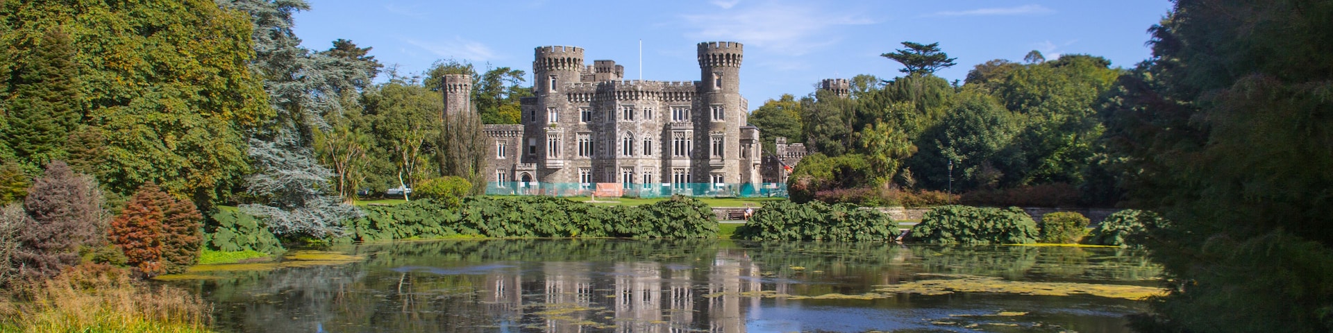 A castle with a moat and lush greenery.