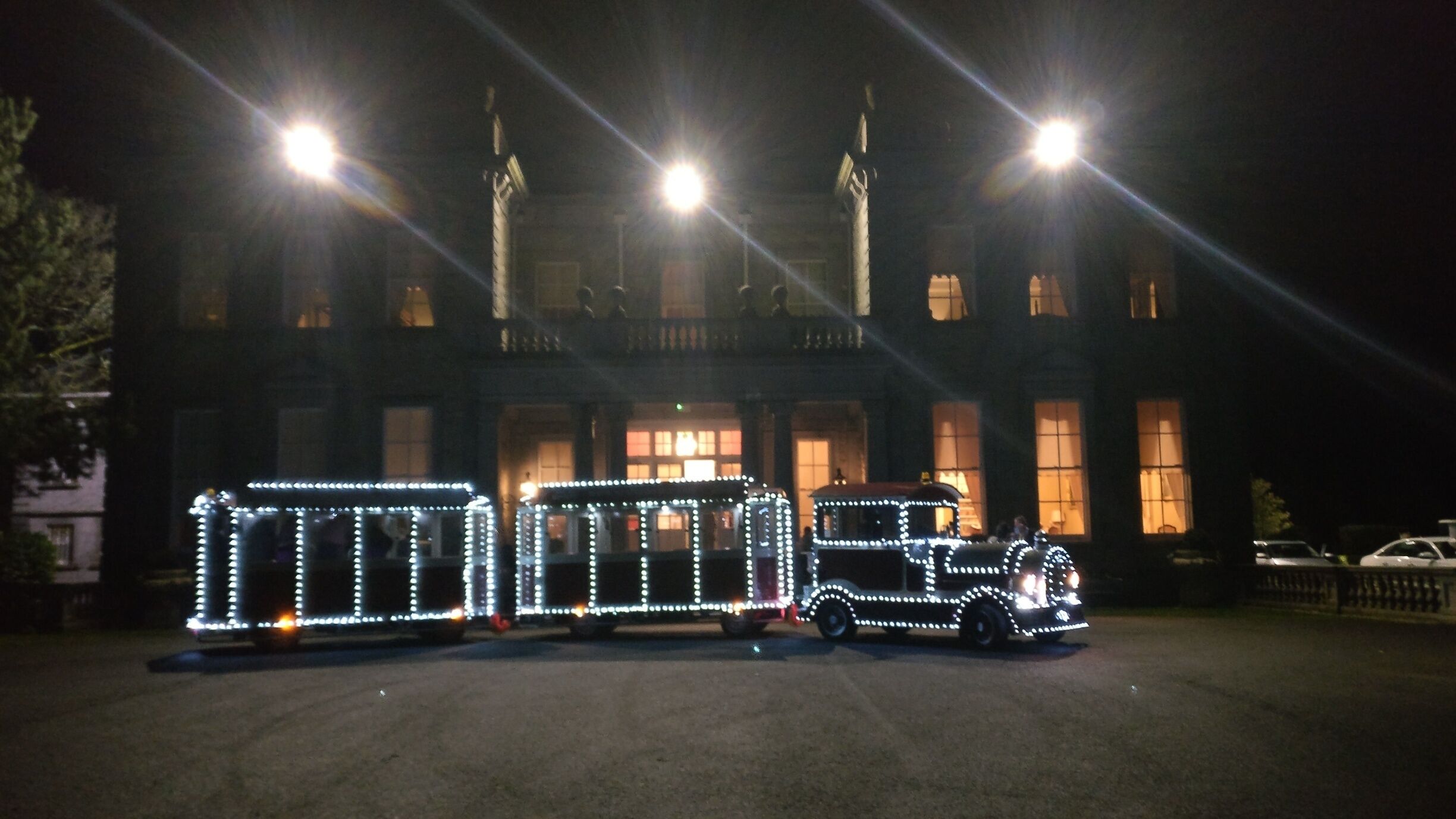 A building with illuminated train car replicas in front.