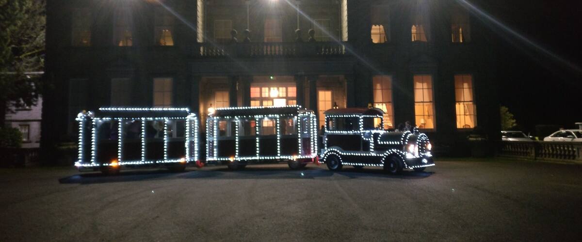 A building with illuminated train car replicas in front.