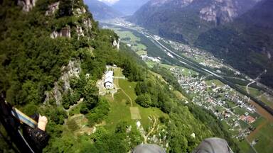 Paisagem montanhosa com um rio, um pequeno povoado e uma igreja.