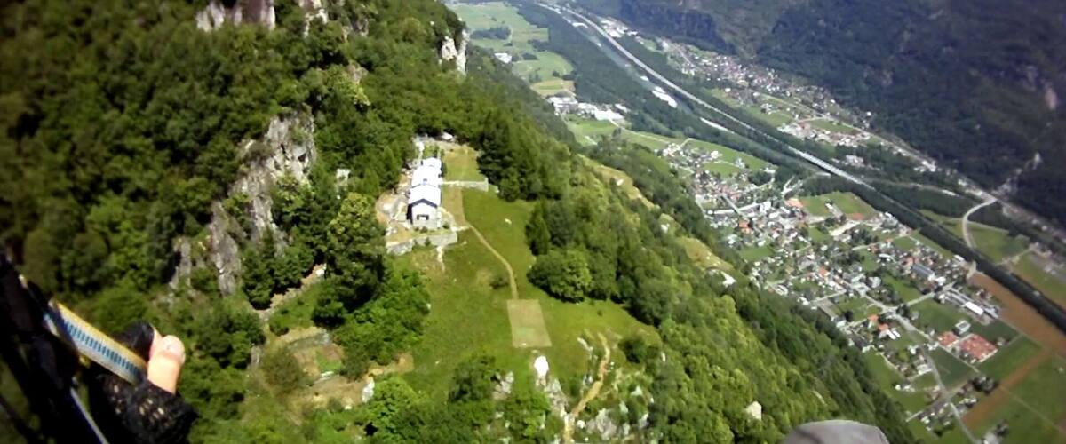 A mountainous landscape with a river, a small settlement, and a church.