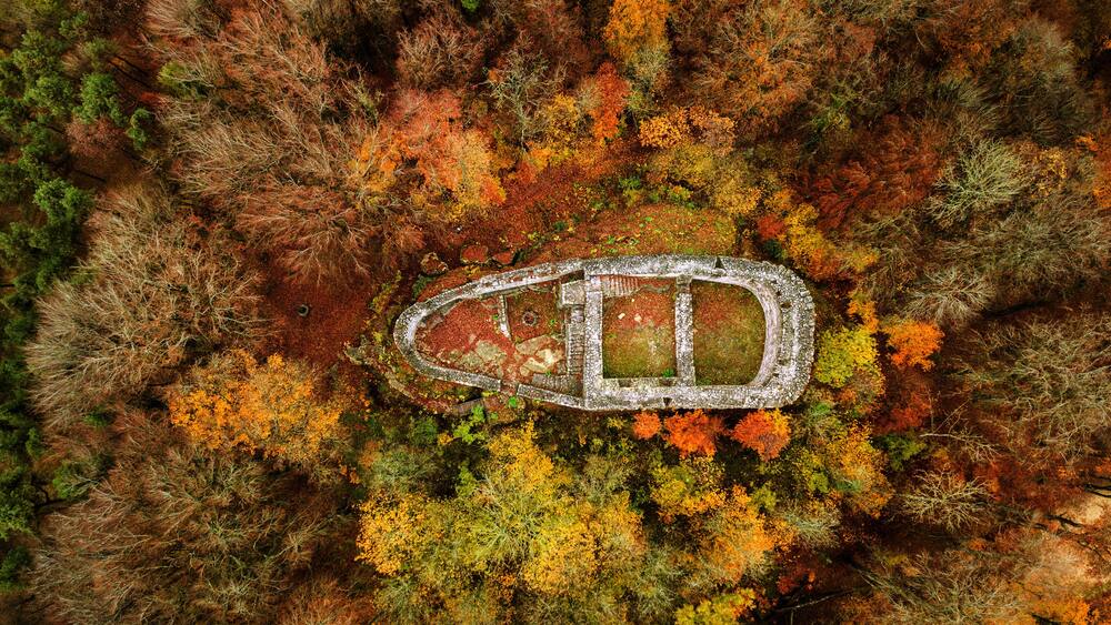 The old fort ruins of Alt Wartburg among the colorful autumn forest trees by drone aerial photography