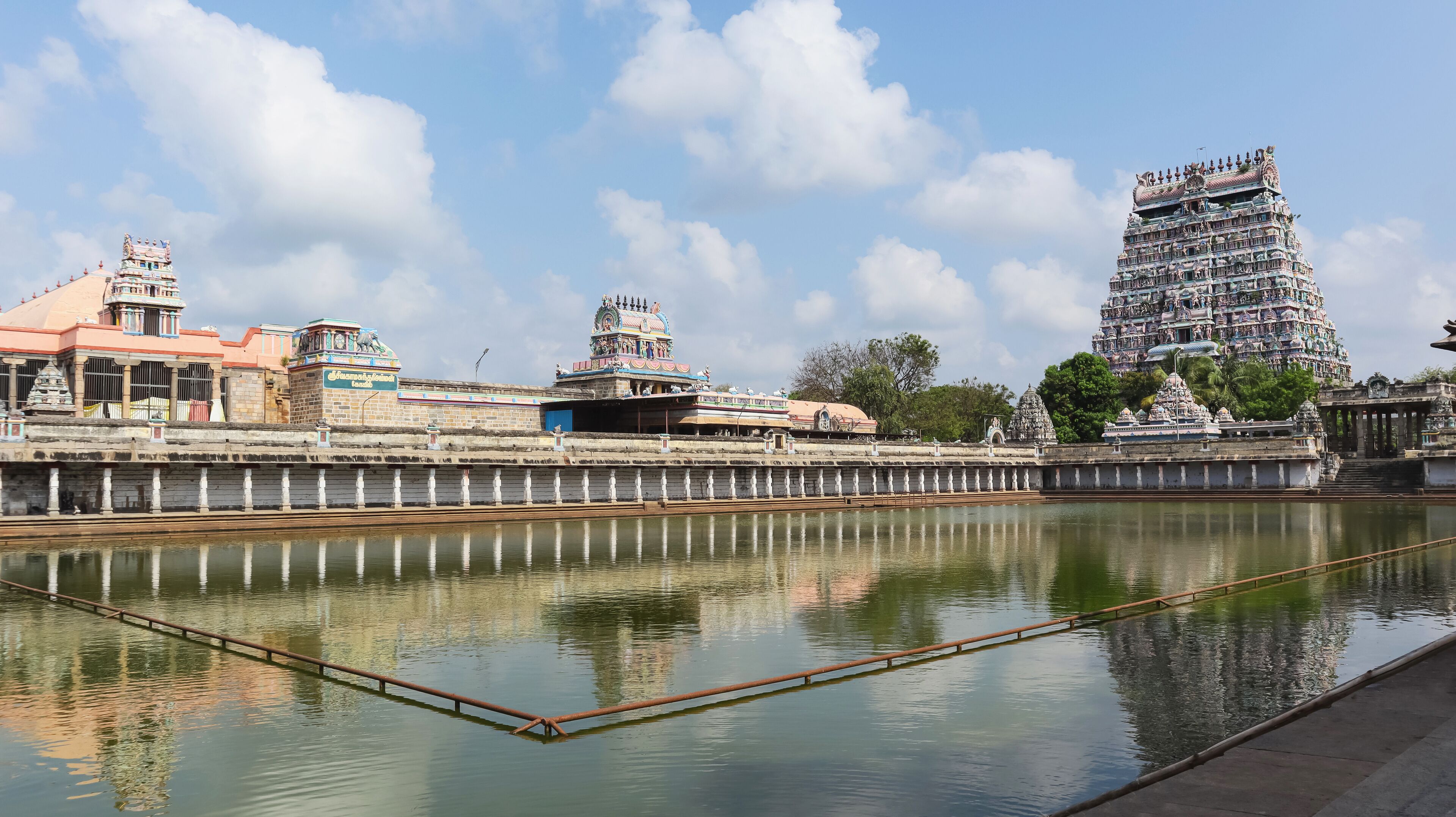 A temple complex with a large, multi-tiered tower and a calm river in the foreground.