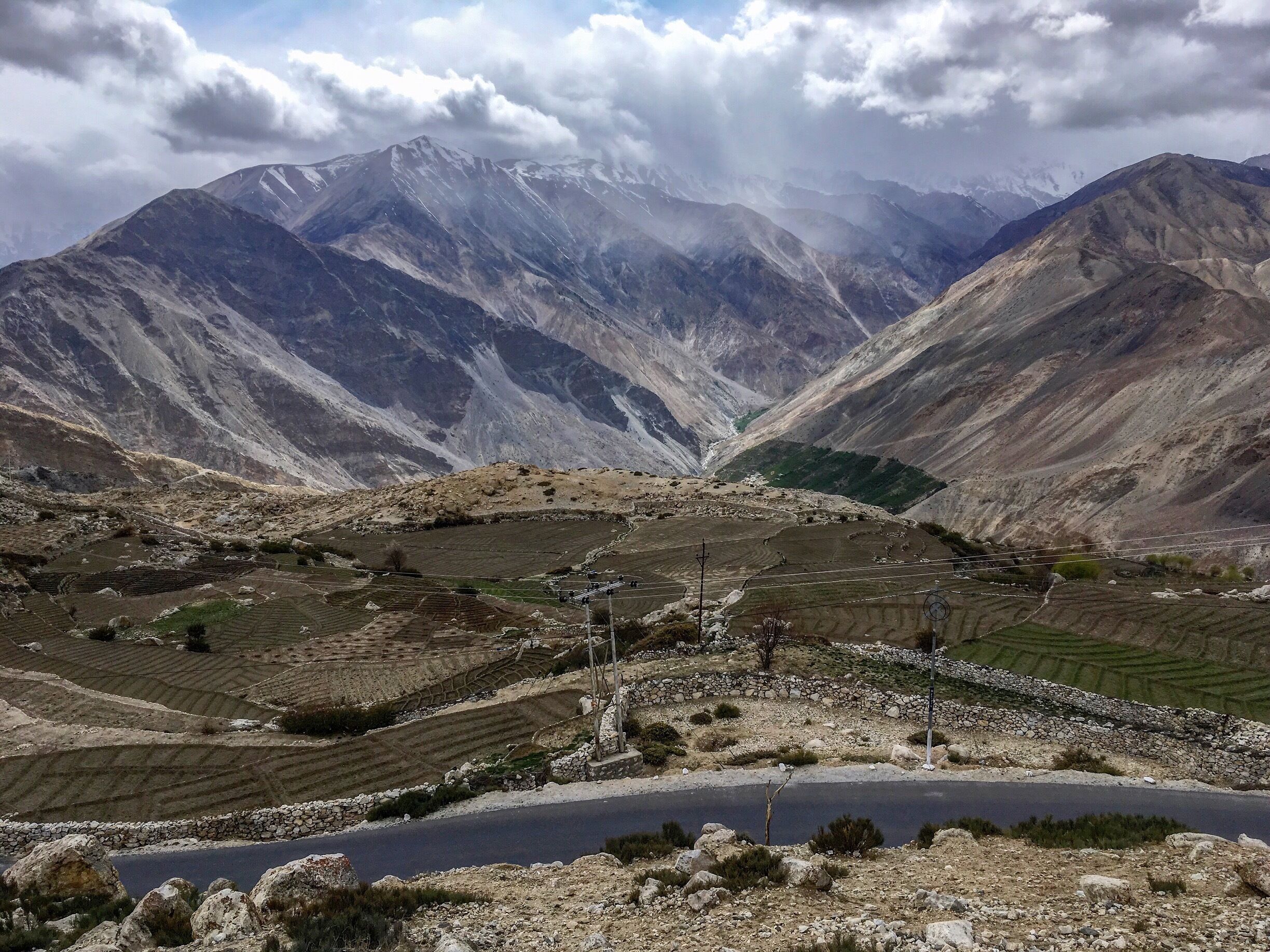 Terraced fields, a winding road, and snow-capped mountains.